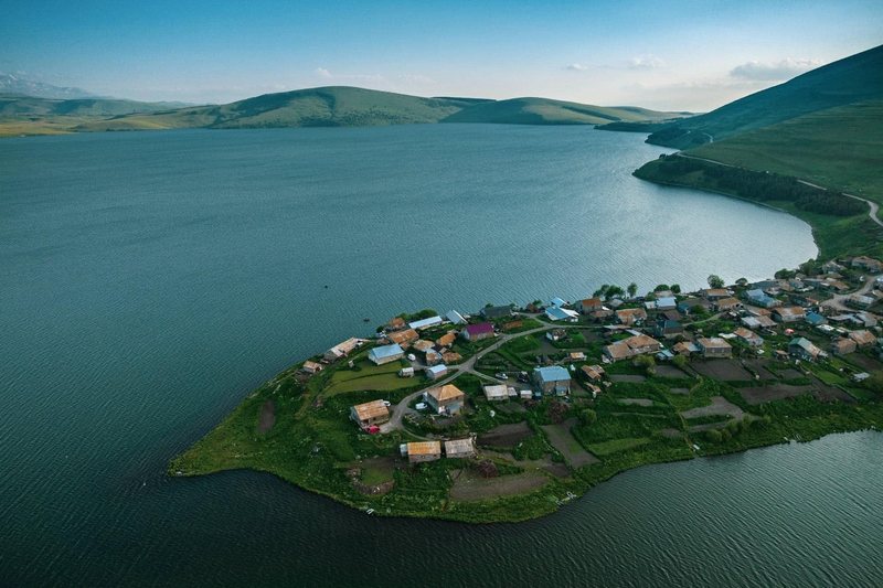 A village on a green peninsula reaching into a mountain reservoir