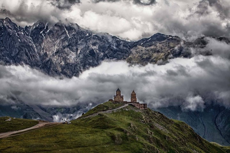 Gergeti Trinity Church on its green hill below the snow-wrapped peak of Mt Kazbek near Stepantsminda