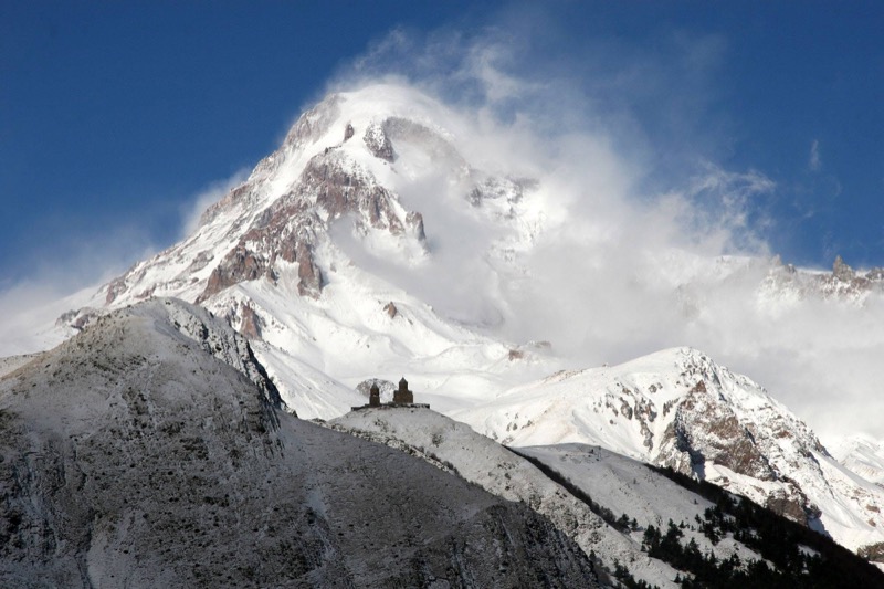 The snow-capped pyramidal peak of Mt Kazbek rising above the valley