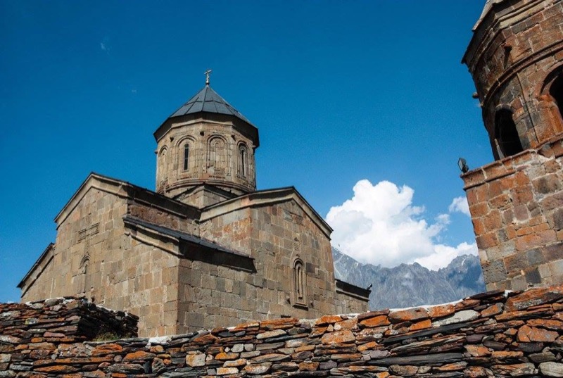 Gergeti Trinity Church with the stone bell tower and Caucasus behind