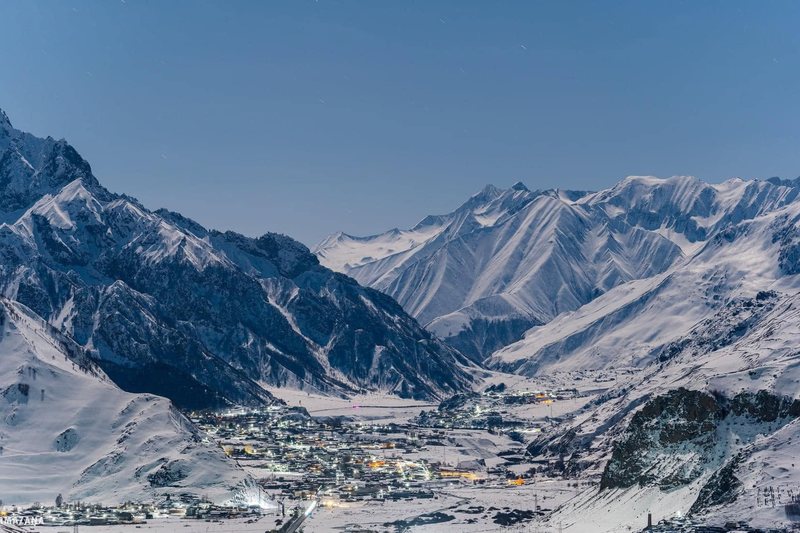 The town of Stepantsminda in its valley below the snow-capped wall of the Greater Caucasus