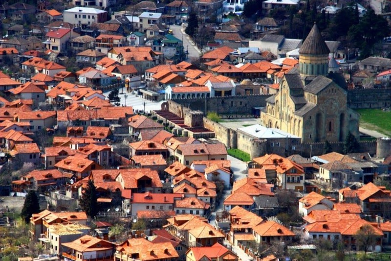 The tall stone walls and tower of Svetitskhoveli Cathedral rising above the rooftops of Mtskheta