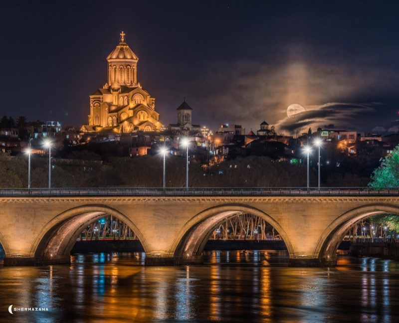 The illuminated bridges of Tbilisi reflected in the Mtkvari river at night